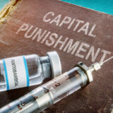 Book that say capital punishment with a bottle of Pentobarbital and syringe